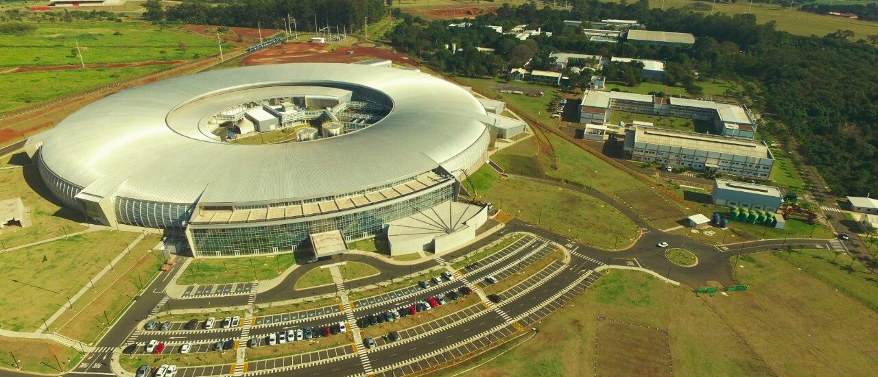 Pesquisador em um laboratório de alta tecnologia ajustando equipamentos ópticos de precisão sob luz azulada.