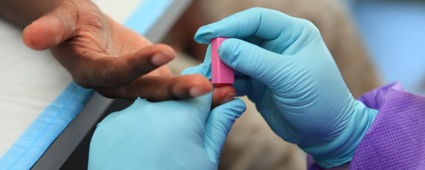 Médico realizando exame de sangue em paciente idoso em um consultório iluminado.