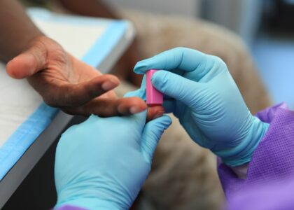 Médico realizando exame de sangue em paciente idoso em um consultório iluminado.