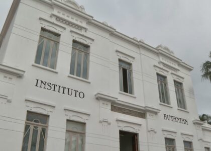 Cientista de jaleco branco utilizando uma pipeta de precisão para manipular amostras em tubos de ensaio dentro de um laboratório de virologia moderno.