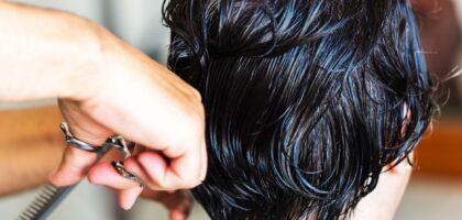 Mulher de cinquenta anos olhando preocupada para uma escova de cabelo com fios caídos em um banheiro iluminado.
