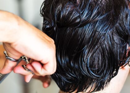 Mulher de cinquenta anos olhando preocupada para uma escova de cabelo com fios caídos em um banheiro iluminado.