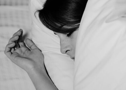 Homem de meia-idade sentado na beira da cama à noite, massageando a panturrilha com expressão de desconforto sob uma luz suave de abajur.